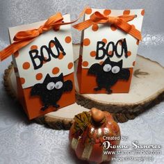 two halloween treat bags sitting on top of a piece of wood next to an orange pumpkin