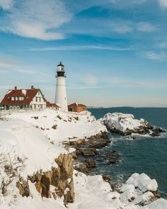 a light house sitting on top of a snow covered cliff next to the ocean