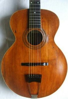 an old wooden guitar sitting on top of a white surface with the strings still attached