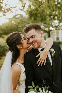 a bride and groom kissing in front of trees