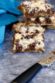 chocolate and coconut bars cut into squares with a knife next to them on a table