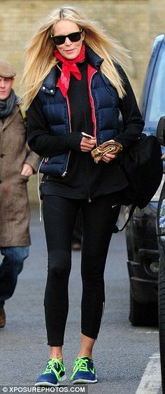 a woman in black jacket and green shoes walking down street with other people behind her