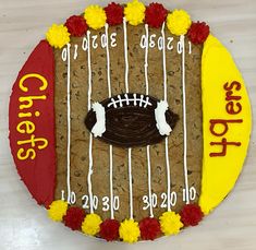 a cookie decorated with footballs and flowers on top of a white table next to a sign