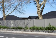 an empty street in front of houses with trees and bushes on the side of the road