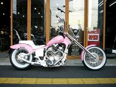 a pink motorcycle parked in front of a building