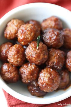 a white bowl filled with meatballs on top of a red cloth