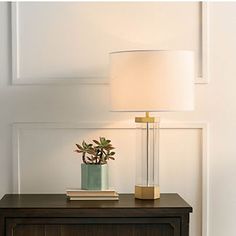 a table with a lamp and a book on it next to a wall in a room