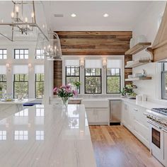 a large kitchen with white cabinets and marble counter tops, along with wood paneling on the walls