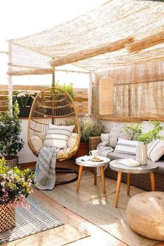 an outdoor patio with wicker furniture and potted plants on the floor, along with a hanging rattan chair