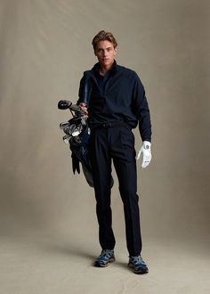 a man in black shirt and white gloves standing next to a motorbike on grey background