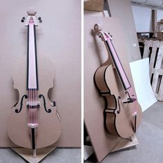 a violin made out of cardboard sitting on top of a wooden stand next to another instrument