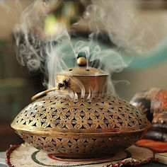 a teapot with steam rising from it on top of a table next to other items