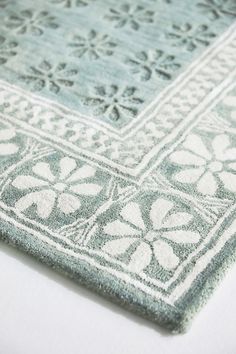 a blue and white area rug with an intricate design on the bottom, in front of a white background