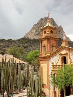 an old church in the mountains with cactus trees