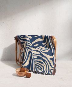 a blue and white blanket sitting on top of a wooden chair next to a basket