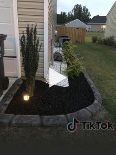 a small garden area with black gravel and lights in the corner, next to a house