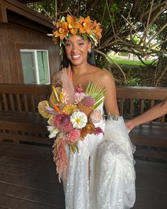 a woman in a white dress holding a bouquet of flowers and wearing a flower crown