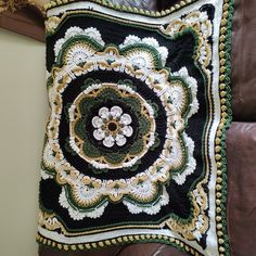 a crocheted pillow is hanging on a leather couch with a brown chair in the background