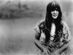 black and white photograph of a woman with long hair standing in front of a body of water