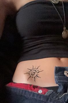 a woman's stomach with a sun tattoo on the side, and her belly