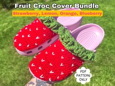 two crocheted strawberry slippers on top of each other in front of green grass