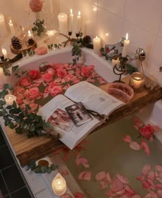 a bathtub filled with flowers and candles next to a book on top of it