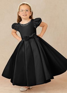 Have your flower girl dressed to impress your friends and family while she wears our matte satin little ballgown, Jewel. Her neckline is jeweled with hand sewn beading, puff sleeves, and a beautiful bow belt that sits atop a full box-pleat tea length skirt. We have matching pearls at the sleeves and a removable back bow. Black Tie Wedding Attire, Satin Flower Girl Dresses, Black Flower Girl, Black Flower Girl Dress, Gothic Wedding Theme, Tea Length Flower Girl Dress, Recital Dress, Dresses In Black, Plus Size Bridal Dresses