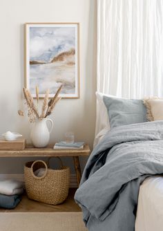 a bedroom with white walls and blue linens on the bed, along with a wicker basket