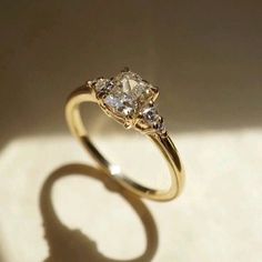 a yellow gold ring with two diamonds on it's sides, sitting on a white surface