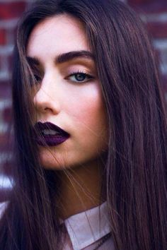 a woman with long brown hair and dark lipstick