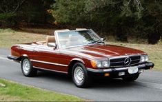 a red convertible car driving down a road