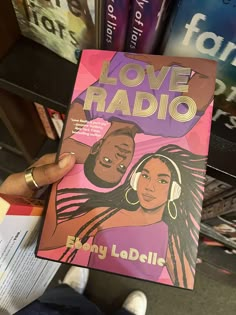 a person holding up a book in front of bookshelves with love radio written on it