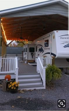 an rv parked under a covered porch with stairs leading up to the front door and side entrance