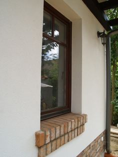 a window on the side of a house with brick and wood trimming around it