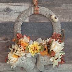 a wreath decorated with flowers and burlocks hanging on a wooden door hanger