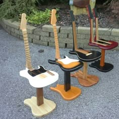 three guitars sitting on top of wooden stools