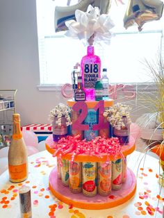 a birthday cake that is decorated with confetti and bottles on the table in front of balloons