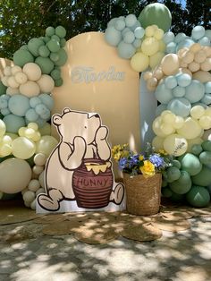 there is a large balloon arch with balloons on it and a teddy bear holding a basket