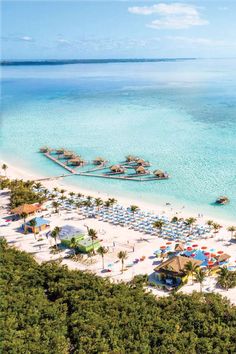 an aerial view of the beach and ocean with palm trees, umbrellas and huts