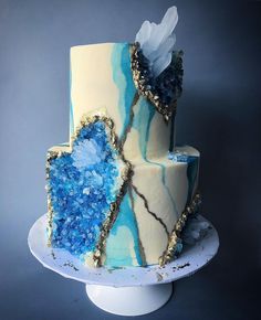 a three tiered cake with blue and white icing on it's side