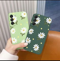 someone holding up their phone case with daisies painted on the front and back sides