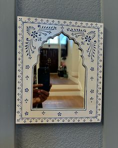 a person taking a photo with their cell phone in front of a mirror on the wall