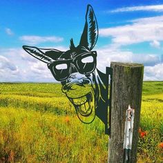 a wooden post with a drawing of a dog wearing sunglasses on it's face