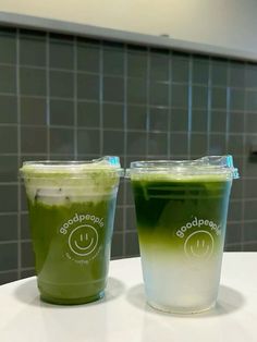 two green drinks sitting on top of a counter