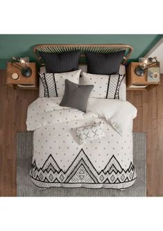 a bed with black and white comforters in a room next to a wooden floor