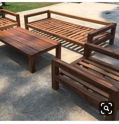 two wooden benches sitting next to each other on a cement ground near grass and trees