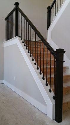 an empty staircase with black railing and wood handrails