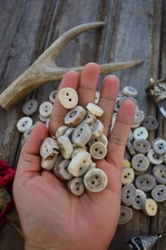 a hand is holding some buttons in front of deer antlers