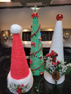 three decorated christmas trees sitting on top of a stove