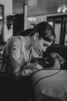 a woman with tattoos on her arm is holding a cat and looking down at it